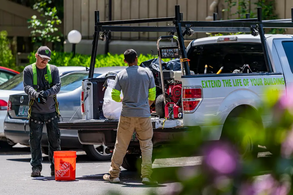 Two HOA Services crew members at a lettered pickup reading Extend the life of your building